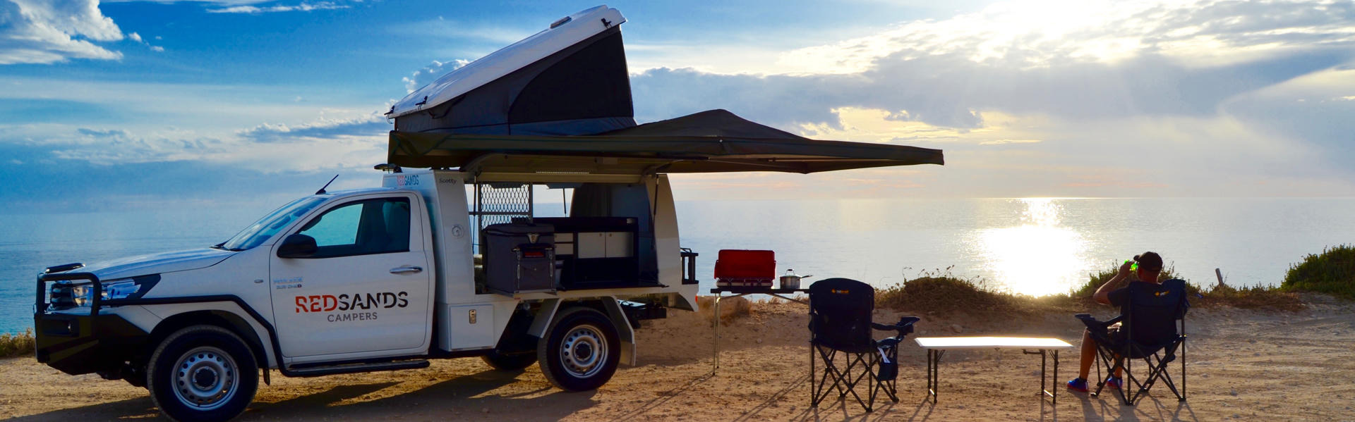Camper mit Campingstühlen am Meer