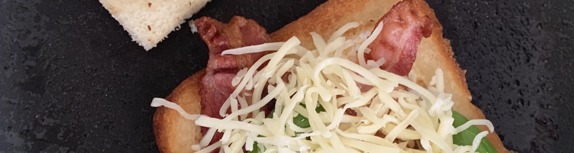 Toastscheibe mit knusprigem Speck und Käse in der Pfanne