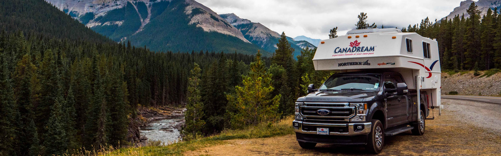CanaDream Maxi Travel Camper in Kanada vor Berg-, Fluss- und Waldkulisse