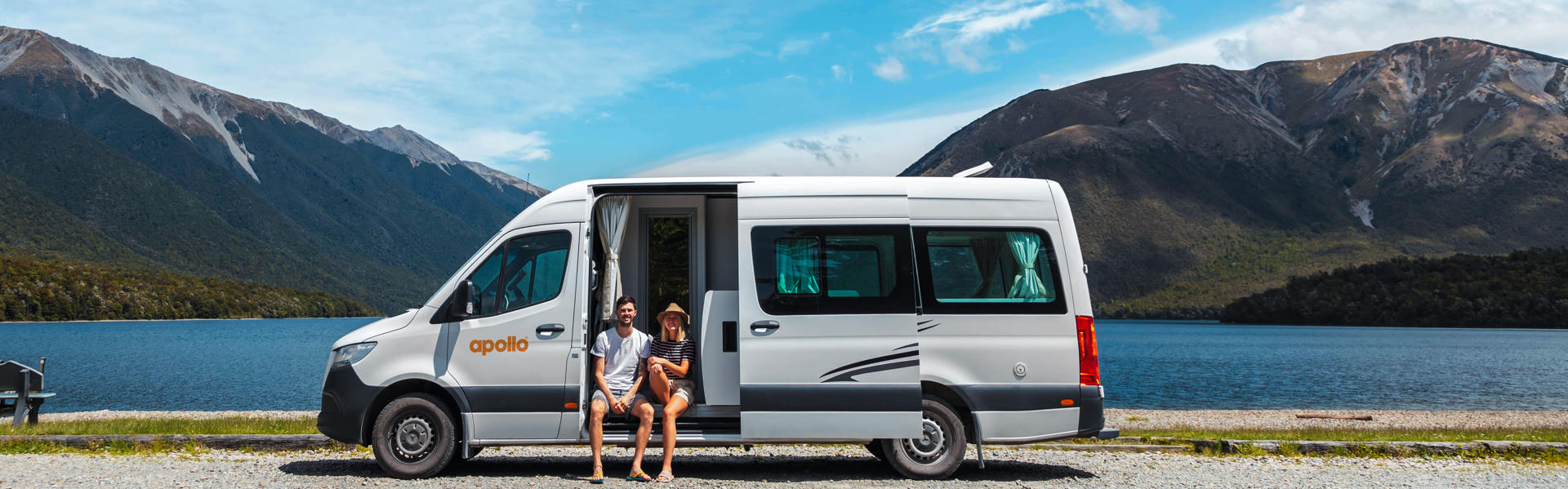Euro Tourer von Apollo Motorhomes mit 2 Personen vor See mit Bergen in Neuseeland