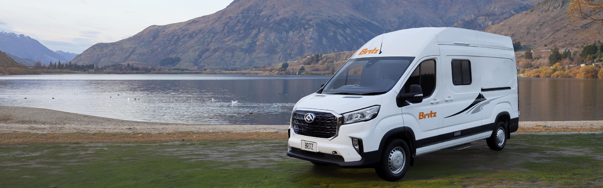 Hitop Camper von Britz Rentals für 2 Personen fahrend auf einer schmalen Straße zwischen Bäumen in Neuseeland