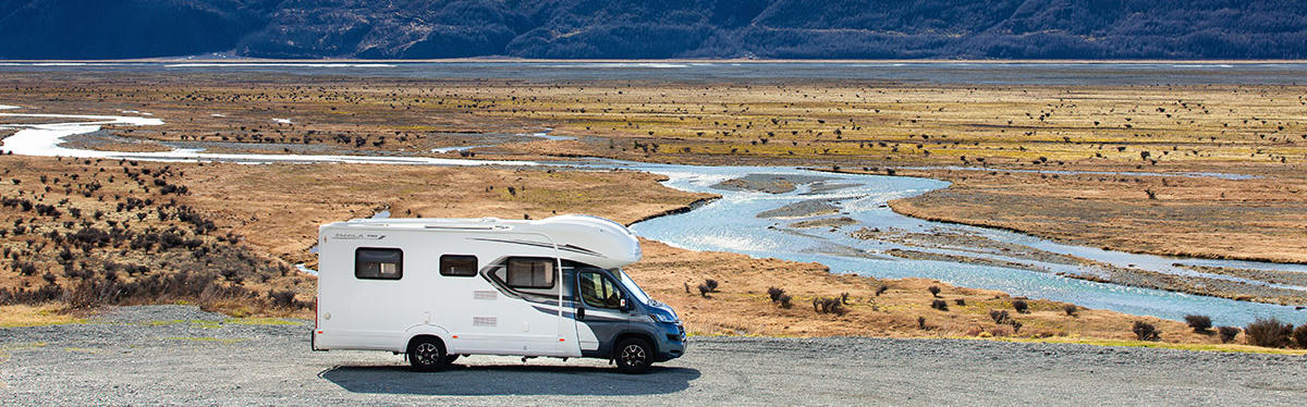 Camper auf Wieseo vor einem See