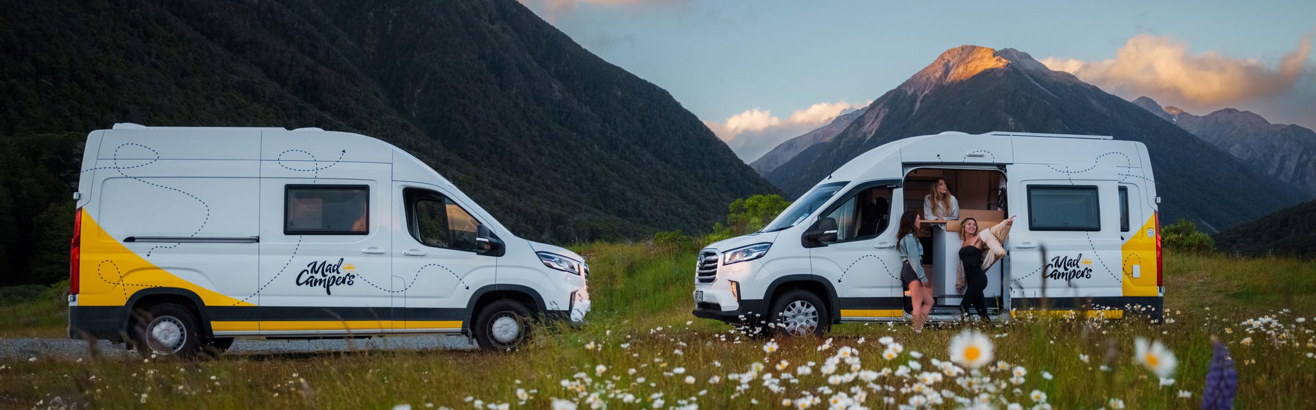 Zwei Mad Camper Explorer auf einer Wiese vor Bergen