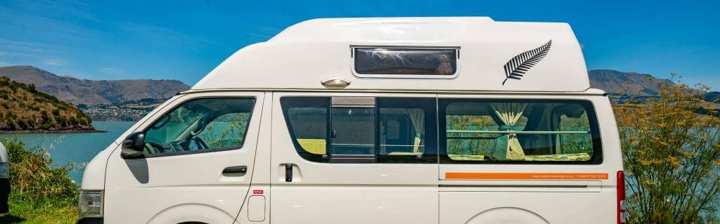 Queenie von Road Runner Rentals steht vor einem See in Neuseeland